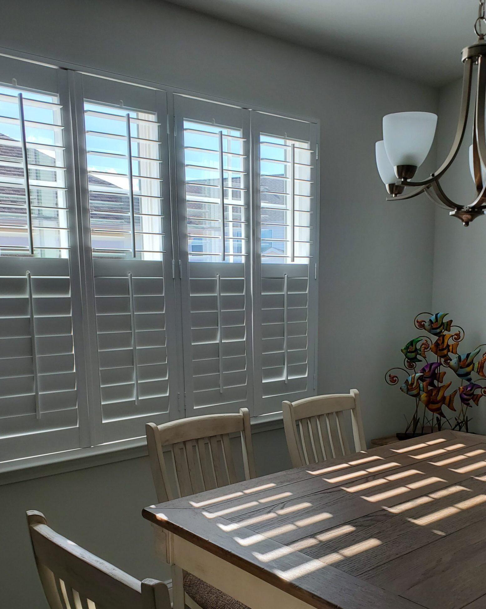 Bright dining area showcasing plantation shutters and a wooden table, emphasizing natural light and home aesthetics.