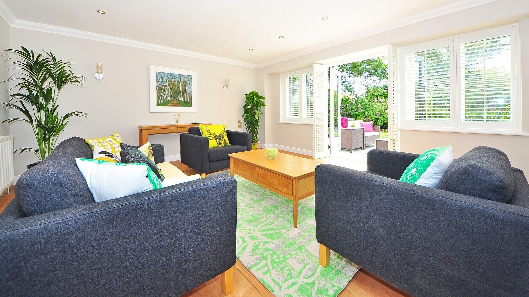 Bright living room featuring energy-efficient premium poly shutters, modern furniture, and indoor plants, highlighting comfort and aesthetic appeal for eco-friendly home improvements.