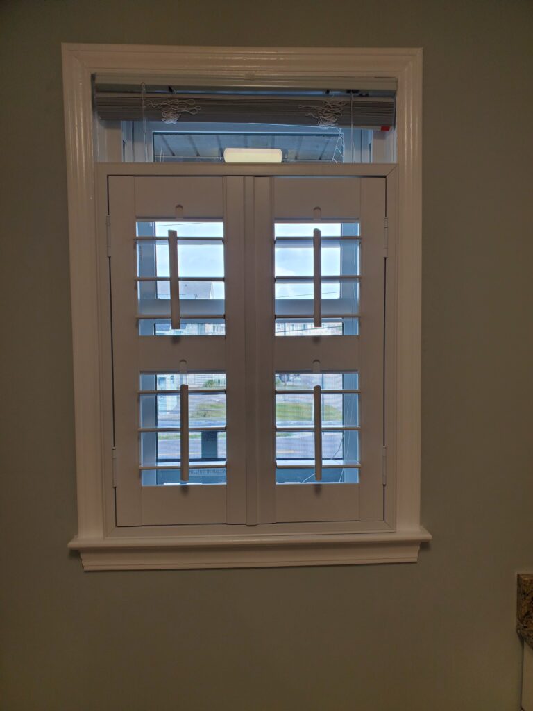 Plantation shutters installed in a window, showcasing a modern design with adjustable slats, enhancing interior aesthetics and functionality for residential spaces.