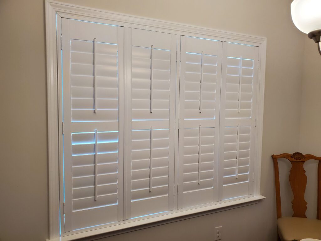 White plantation shutters installed on a window, showcasing a clean and modern design, enhancing the interior space of a home.