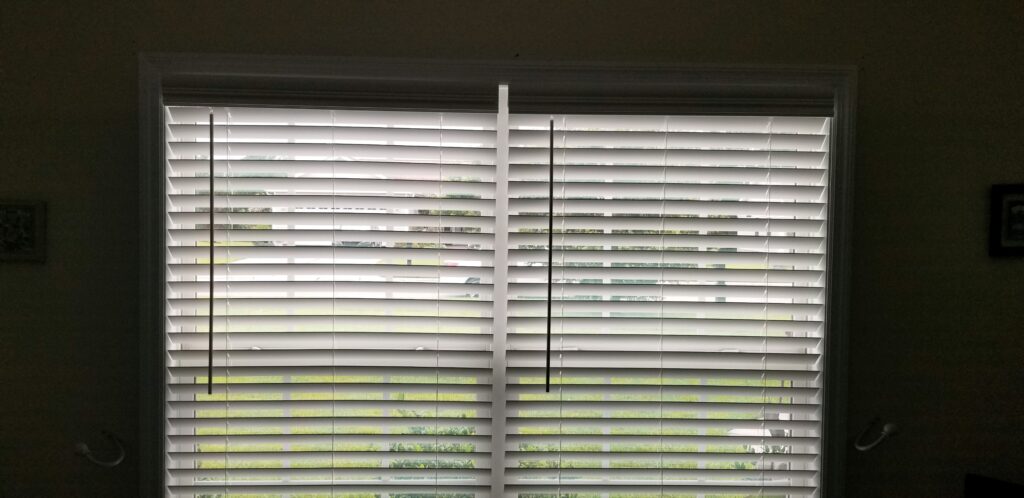 Interior view of faux wood blinds covering a window, showcasing light filtering through the slats, emphasizing stylish window treatment options for enhancing home aesthetics.